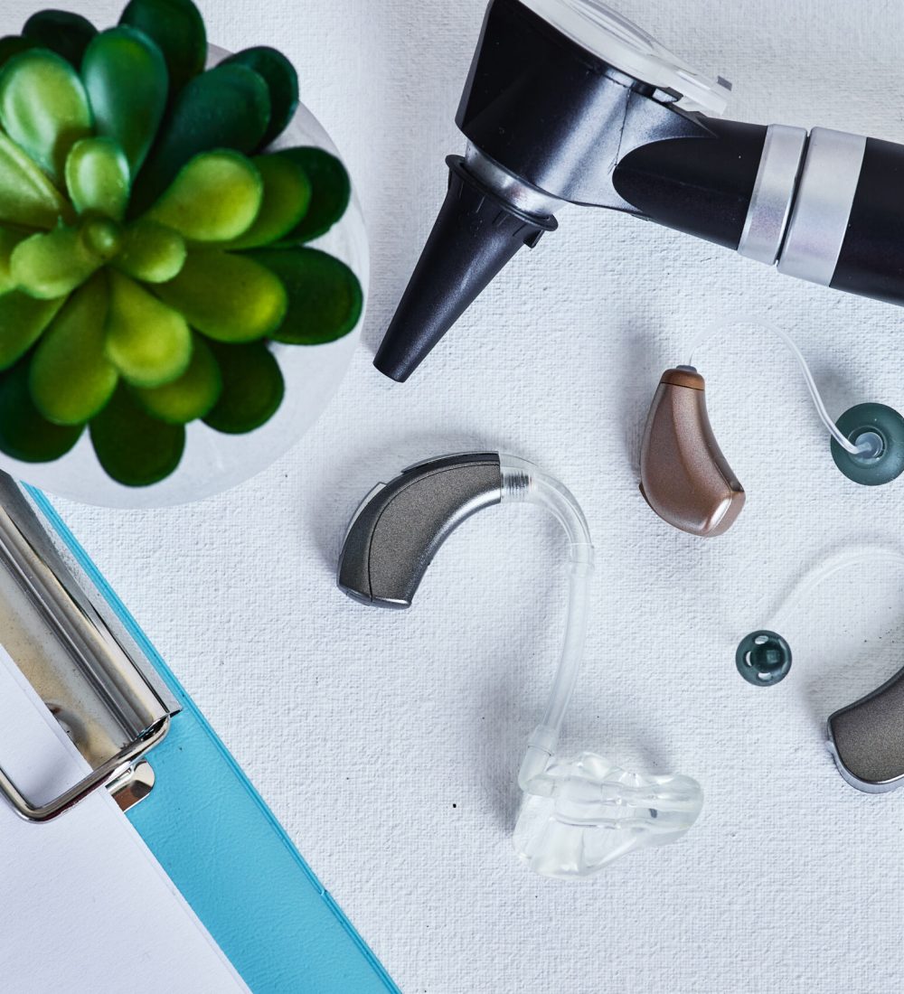 Modern audiology displayed with behind-the-ear hearing aids and otoscope for hear exam on doctor table in hearing clinic. Audiolog