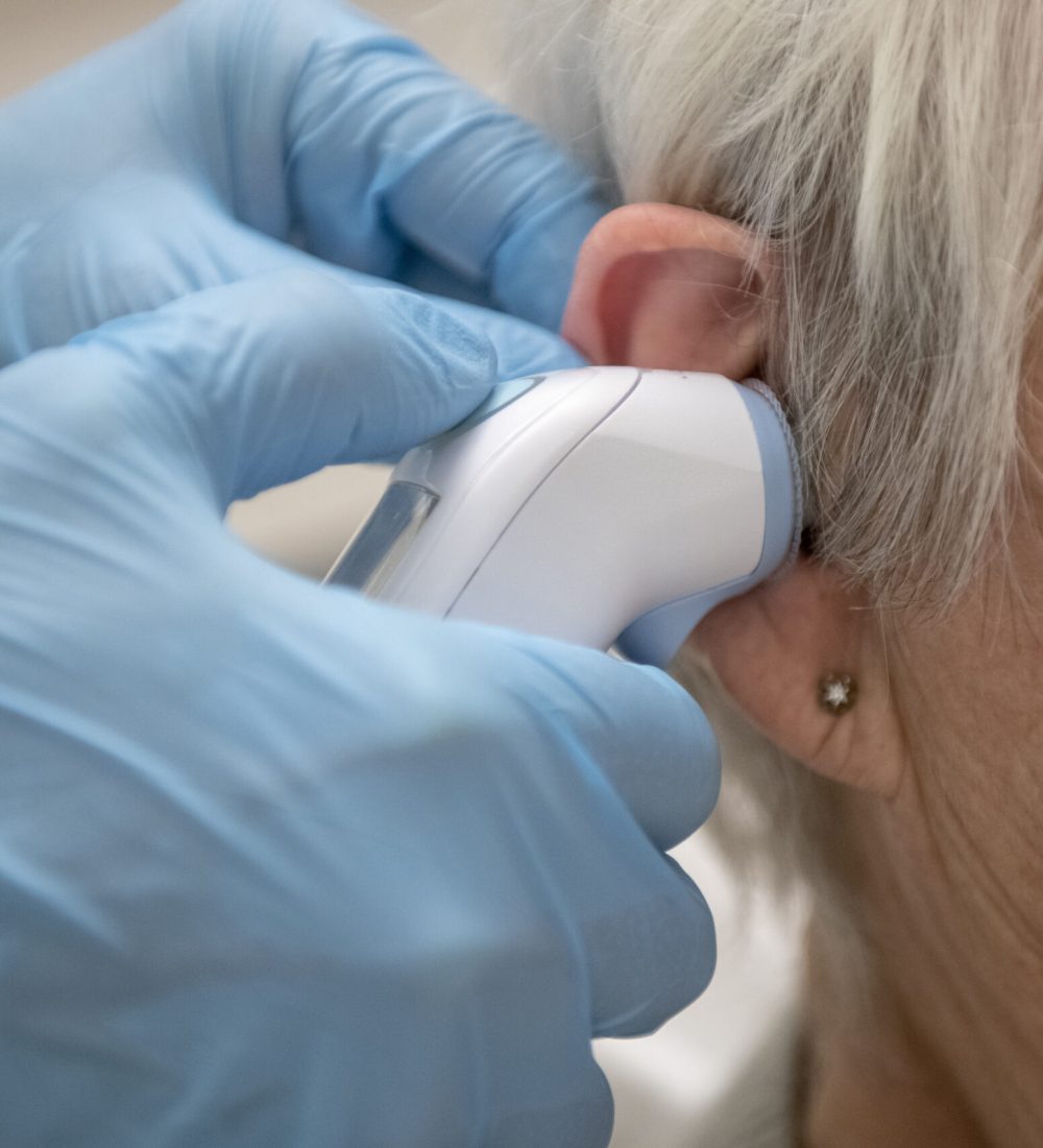 Elderly lady in hospital having her temperature taken by a doctor